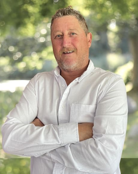 Portrait of Frank Zaino in a white shirt, arms crossed, outdoors